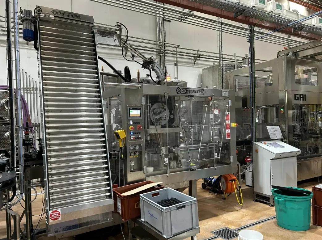 Sparkling wine bottling line with the muselet machine in the foreground